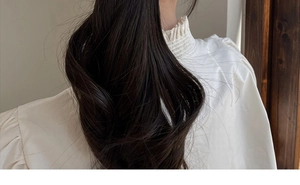 Close-up of elegant long wavy black hair extensions worn with a minimalist hair clip