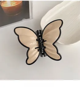 Macro detail of a beige butterfly hair claw clip with black outlines and glossy finish