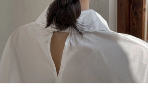 Detail shot of white long sleeve shirt showing unique back slit design and cotton texture