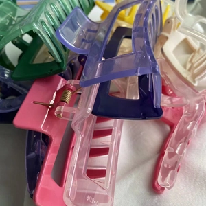 Macro detail of multicolored rectangular shark hair clips with metallic spring on white fabric