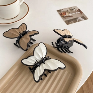 Elegant butterfly hair claws in white and brown tones for a sophisticated ponytail look