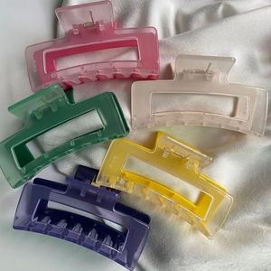 Close-up of five colorful rectangular hair claws set on white fabric background