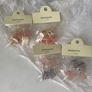 Mini colorful transparent plastic hair claws set in small bags on white background