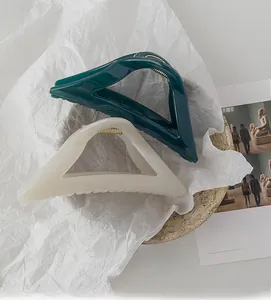 Detail of large green and beige geometric shark hair claws with strong metal springs