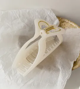 Close-up of cream translucent geometric shark clip with golden metal spring