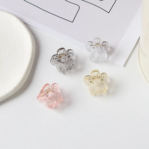 Détail de quatre mini pinces à cheveux fleur en blanc, gris, jaune et rose pastel