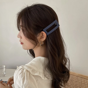 Minimalist matte dark blue rectangle hair clip and gold hoop earrings on model
