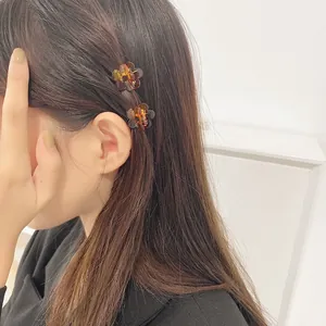 Détail de mini pinces à cheveux fleur ambre de 1,5 cm sur une coiffure latérale