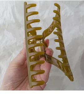 Detail view of a large amber resin hair claw clip with a strong golden metal spring