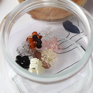 Mini pinces à cheveux fleurs colorées présentées dans un bocal en verre style minimaliste