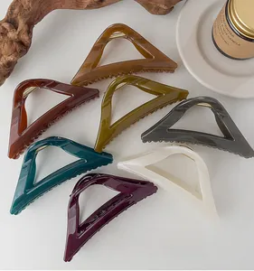 Detail view of seven geometric shark hair clips in assorted colors on a wooden tray