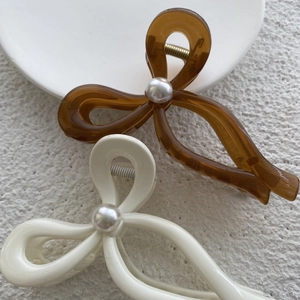 Detail of amber and cream hair claws with pearl accent and durable metal spring