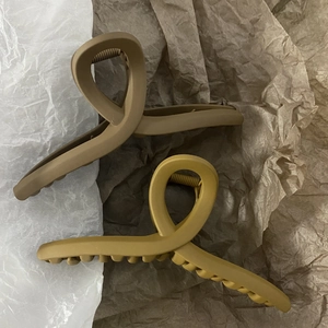 Detail view of large matte brown and mustard yellow hair claws with a cross-loop design