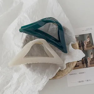 Minimalist geometric hair claws in cream white and dark green on an aesthetic background