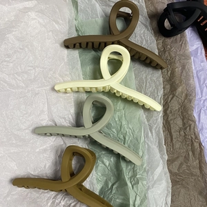 Flat lay macro of large matte 13cm hair claw clips in earth tones on colored crinkle paper