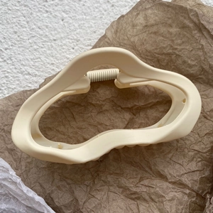 Gros plan d'une grande pince à cheveux mate crème sur papier brun texturé naturel