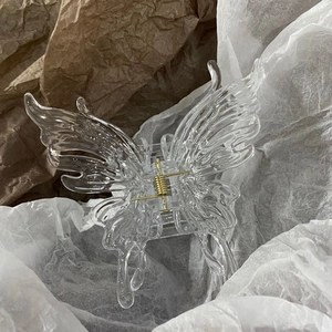Detailansicht einer transparenten Schmetterlings-Haarklammer mit goldener Metallfeder