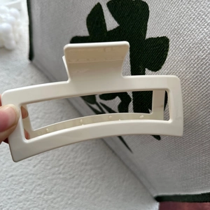 Gros plan sur une pince à cheveux rectangulaire blanc crème avec dents antidérapantes et ressort