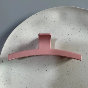 Pince à cheveux rose brillante minimaliste sur un plateau en céramique pour cheveux longs