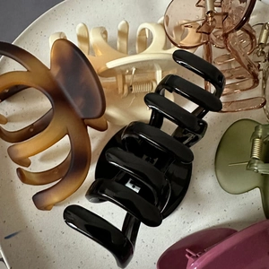 Close-up of assorted large pumpkin hair claws in various matte colors on a ceramic tray