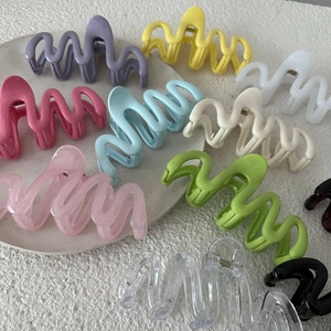 Dettaglio di pinze per capelli ondulate da 13cm in colori pastello su un vassoio