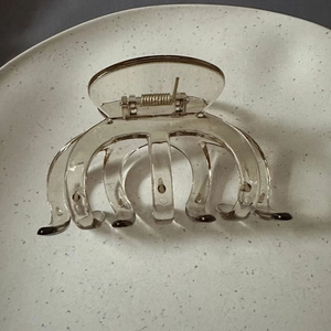 Top view of a large brown pumpkin claw clip on a textured white plate with metal spring
