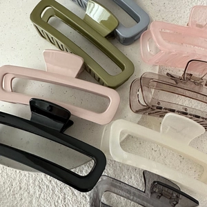 Flat lay showing various colors of long rectangular hair claw clips on textured background