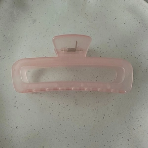 Detail view of large translucent pink rectangular hair claw clip with metal spring
