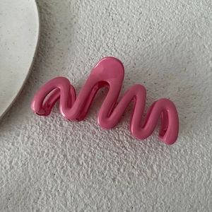 Dettaglio della molletta per capelli ondulata rosa acceso da 13cm con finitura lucida