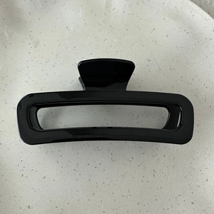 Macro view of large rectangular hollow hair claw clip in glossy black minimalist design
