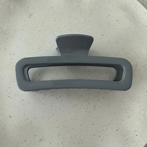 Close-up of minimalist grey rectangular hair claw clip with glossy finish and metal spring
