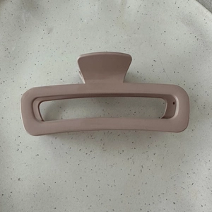 Detail view of a large rectangular matte dusty rose hair claw clip for thick hair styling