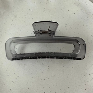 Detail view of large rectangular hollow hair claw clip in transparent smoky grey finish