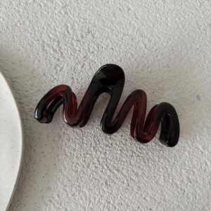 Dettaglio di un mollettone per capelli a onde traslucido bordeaux da 13cm su base
