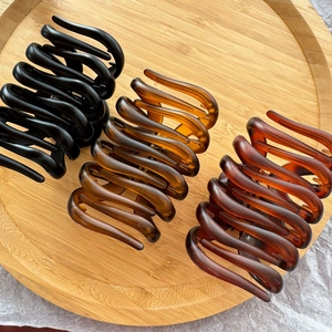 Three-piece large matte pumpkin hair claws in amber and black on a bamboo tray