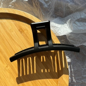 Dettaglio di un fermaglio per capelli nero opaco rettangolare dal design lineare e moderno