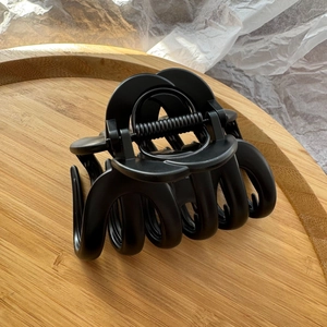 Macro view of large matte black pumpkin hair claw clip on a rustic wooden tray