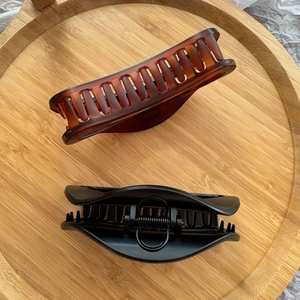 Detail von bernsteinfarbenen und mattschwarzen Haarklammern auf einem Bambustablett