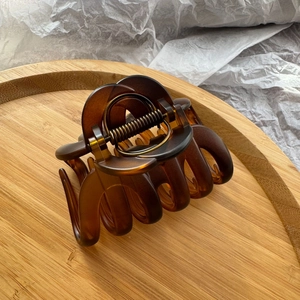 Close-up of tortoise shell pattern hair claw clip on a bamboo tray with a metal spring detail