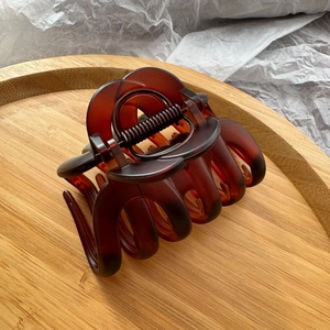 Detail of amber tortoiseshell claw clip with metal spring on a bamboo tray