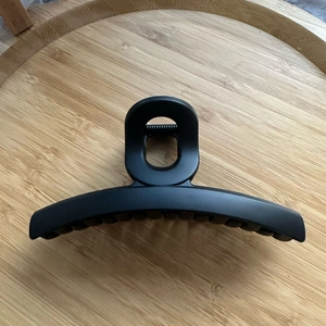 Gros plan sur la pince à cheveux noire mate avec ressort métallique sur bois