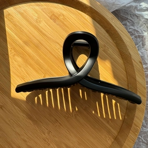 Vue de dessus d'une pince à cheveux ruban noir mat 15cm sur un plateau en bois avec ombres