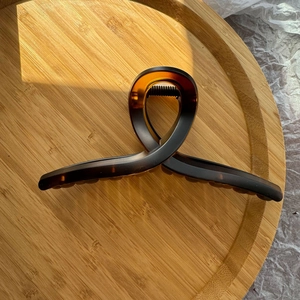 Détail de la pince à cheveux croisée en écaille ambrée avec une texture mate raffinée