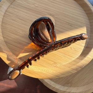 Macro detail of amber tortoise hair claw clip with wooden texture on a wooden tray