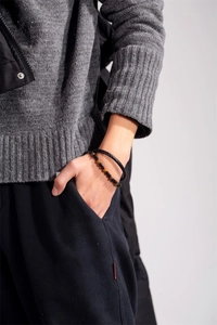 Dettaglio del bracciale multistrato maschile in pelle nera e pietre occhio di tigre