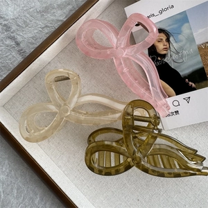 Vue détaillée des pinces à cheveux en résine translucide avec nœuds en rose, beige et vert