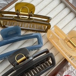 Top view of large jelly colored rectangular hair claws in four colors on a white tray