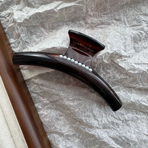 Macro detail of French style tortoiseshell hair claw clip with elegant pearl embellishments