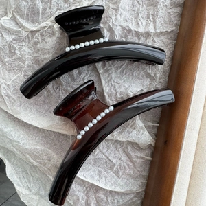 Detail of glossy black and tortoiseshell hair claws featuring embedded white pearls