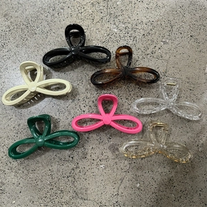 Flat lay of colorful butterfly hair claw clips in various finishes on a textured background